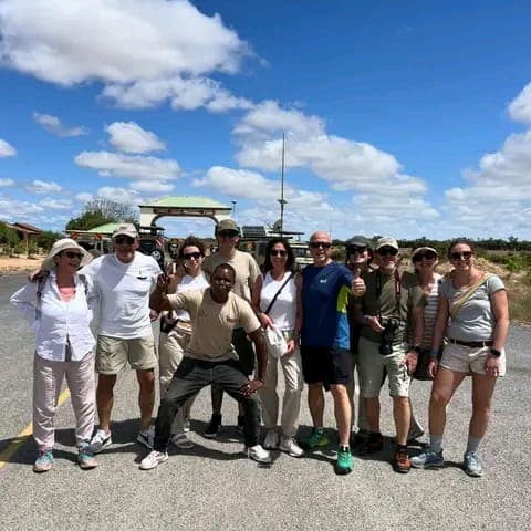 A happy group of travelers with their guide at the Tsavo National Park gate