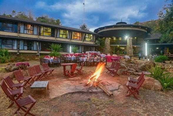An outdoor dining terrace at dusk with a bonfire at a Tsavo safari lodge